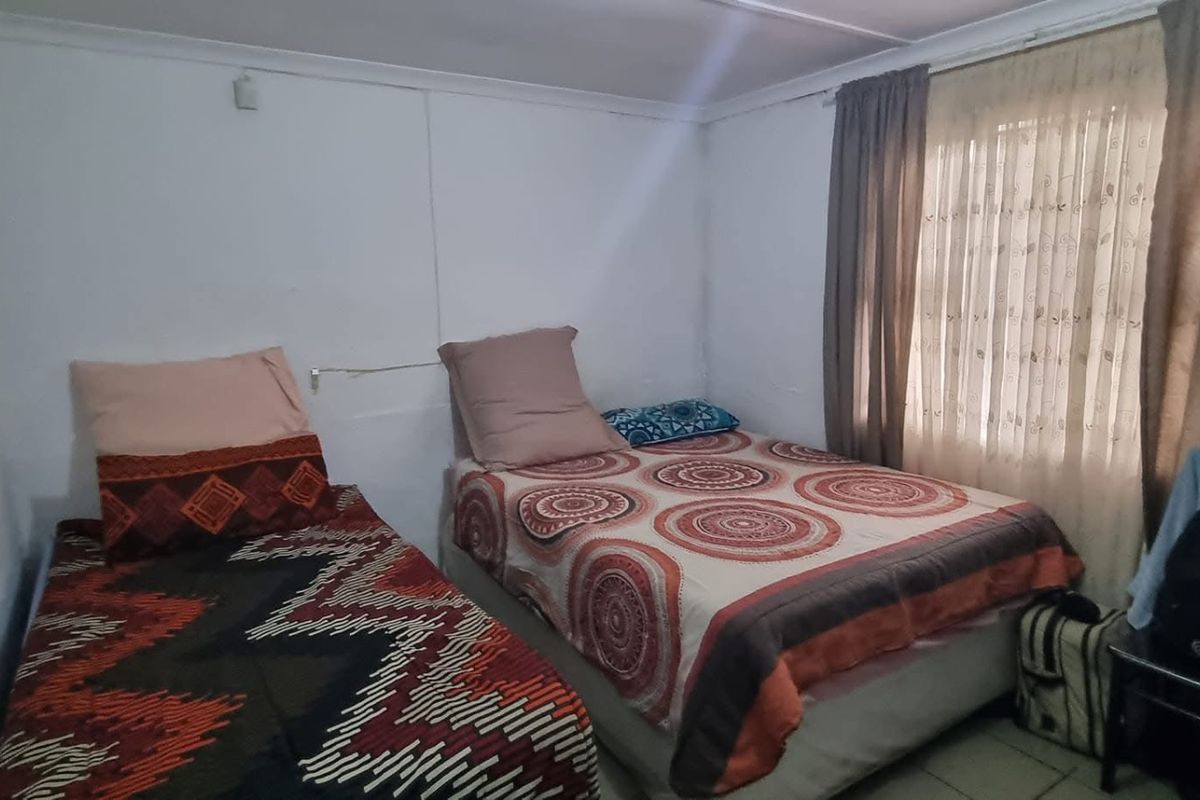 A compact bedroom featuring tiled flooring and window treatments, requiring cosmetic updates to improve the overall finish and appeal.