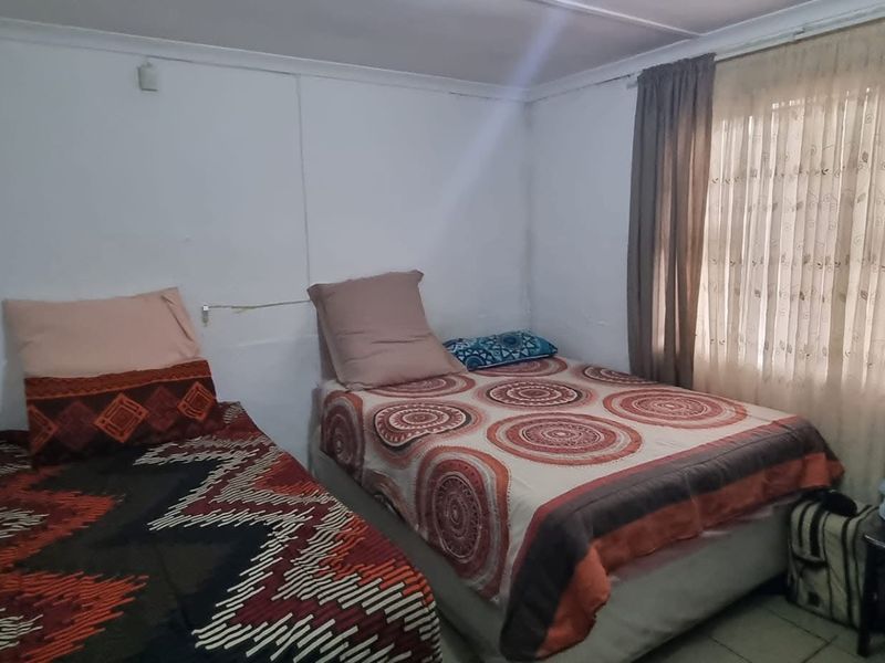 A compact bedroom featuring tiled flooring and window treatments, requiring cosmetic updates to improve the overall finish and appeal.