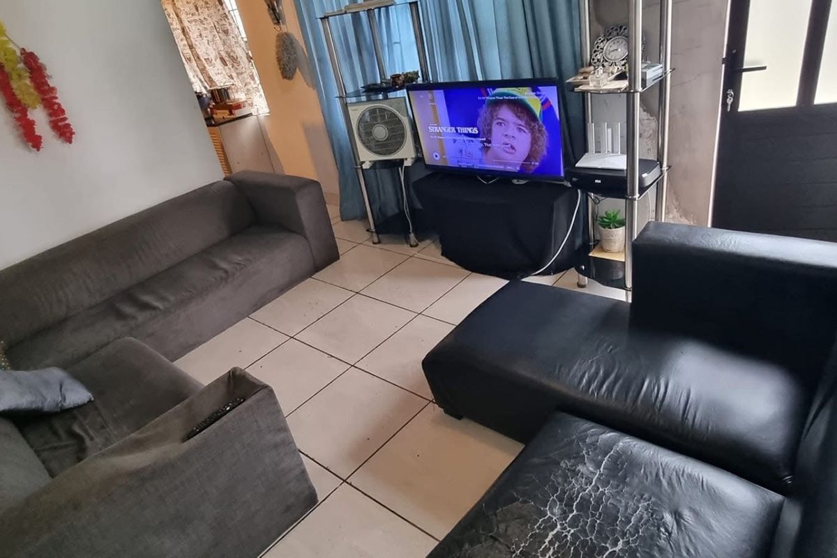 A living room featuring tiled flooring and a glass panel door, providing a functional space with potential for cosmetic updates.