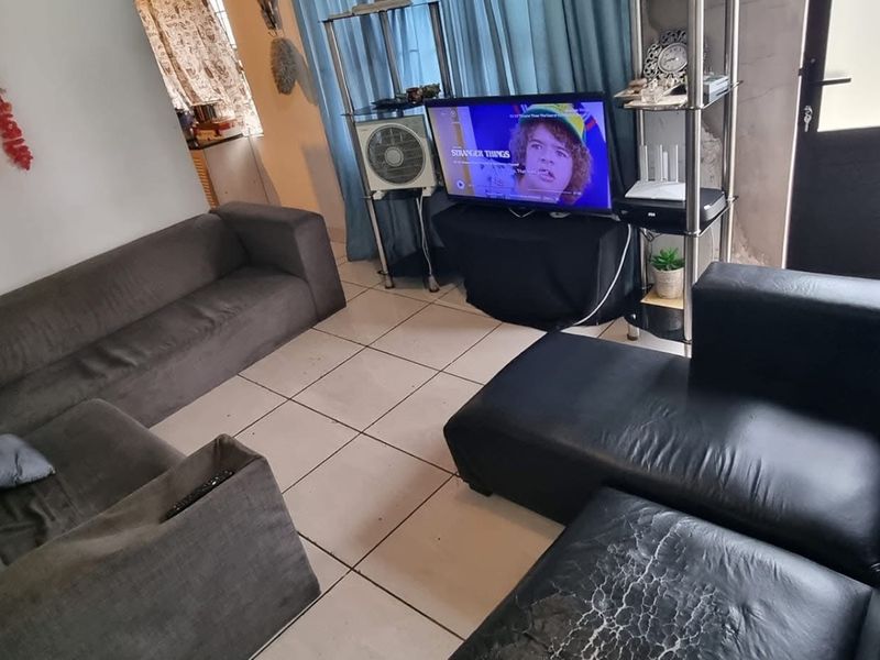 A living room featuring tiled flooring and a glass panel door, providing a functional space with potential for cosmetic updates.