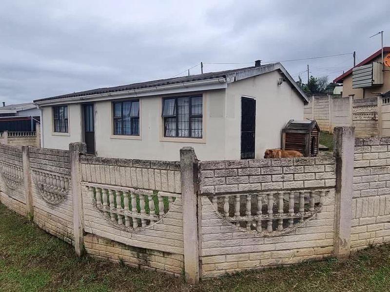 A detached residential property featuring a precast concrete boundary wall and metal window frames, showing signs of exterior weathering and maintenance requirements.