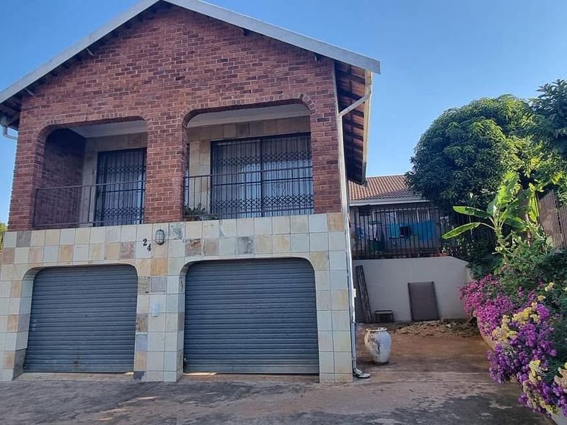 A two-story brick house featuring a double garage with roller doors and an upper-level balcony with security gates.