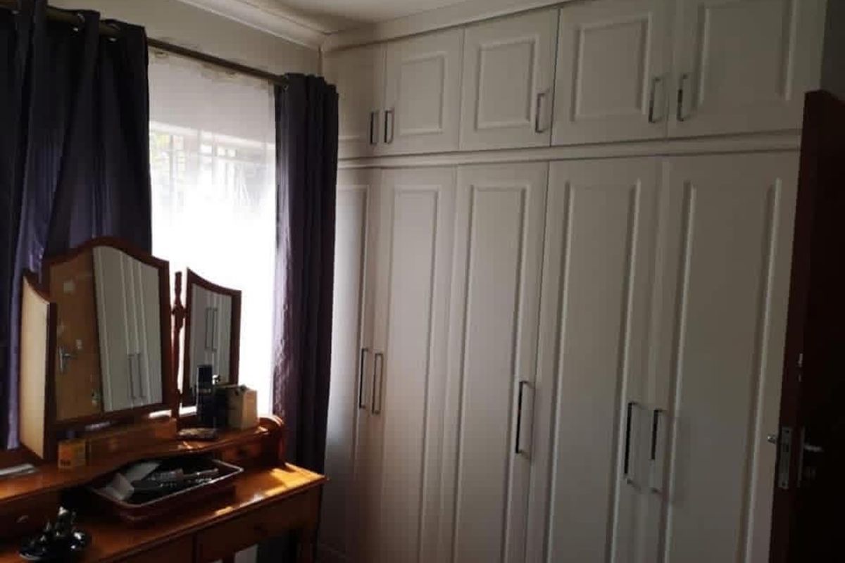 A bedroom featuring extensive built-in floor-to-ceiling cabinetry with classic panel detailing and integrated overhead storage cupboards.