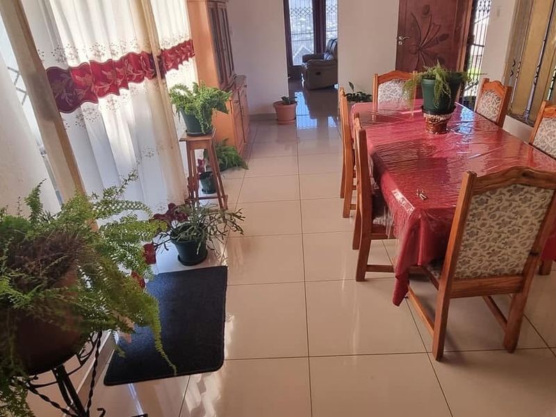 A bright dining area featuring large format floor tiles, natural light from sliding glass doors, and access to an adjacent living space.