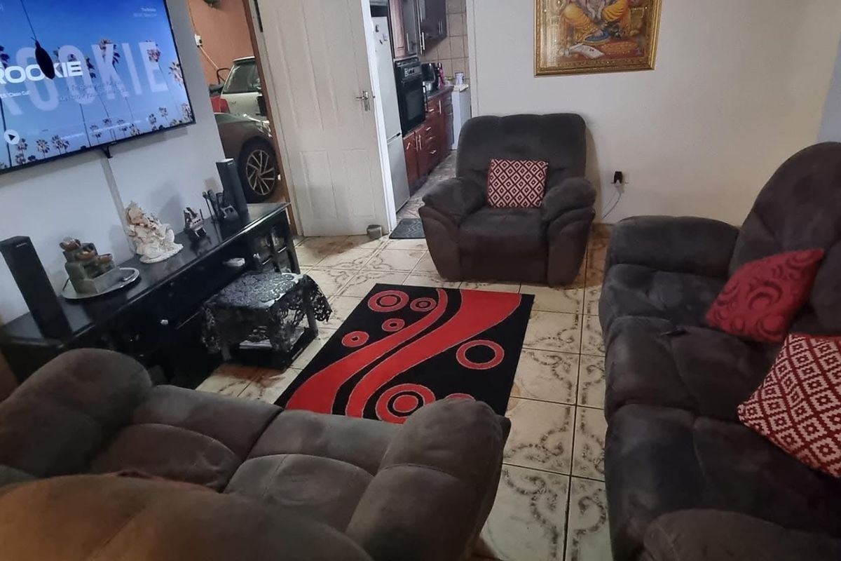 A living room featuring tiled flooring and a view through to the kitchen area.