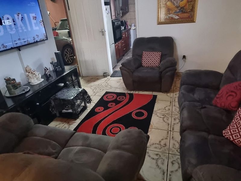 A living room featuring tiled flooring and a view through to the kitchen area.