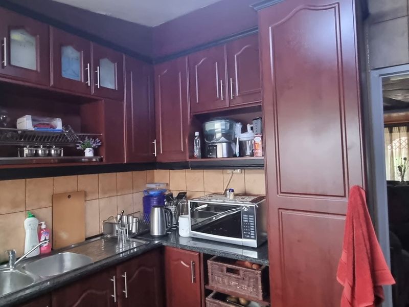 A functional kitchen featuring dark wood cabinetry, a double stainless steel sink, and a tiled backsplash, providing ample storage and workspace.