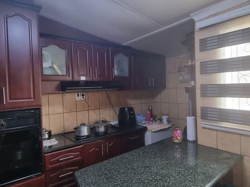 A functional kitchen featuring dark wood cabinetry, granite countertops, a built-in oven, and a tiled backsplash with a window providing natural light.