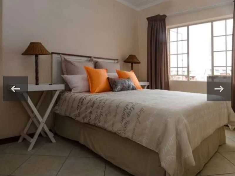 A bedroom featuring tiled flooring and a window with grid detailing, providing natural light and a neutral foundation for interior design.