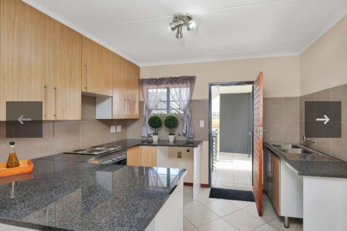 A functional kitchen featuring granite countertops, ample built-in cabinetry, a hob, oven, and a double sink with direct access to an outdoor area.