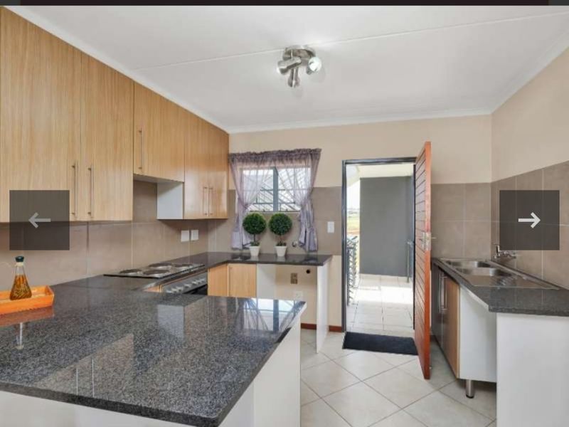 A functional kitchen featuring granite countertops, ample built-in cabinetry, a hob, oven, and a double sink with direct access to an outdoor area.