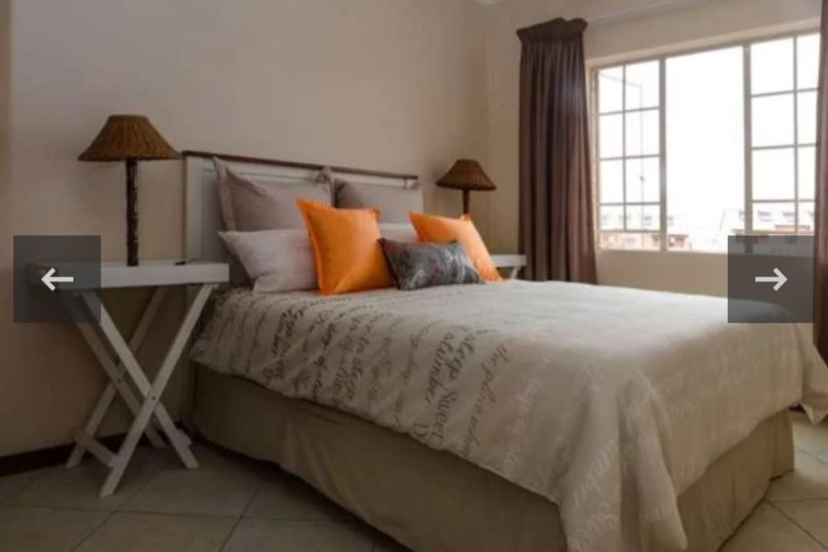 A bedroom featuring tiled flooring and a window with grid detailing, providing natural light and a neutral foundation for interior design.