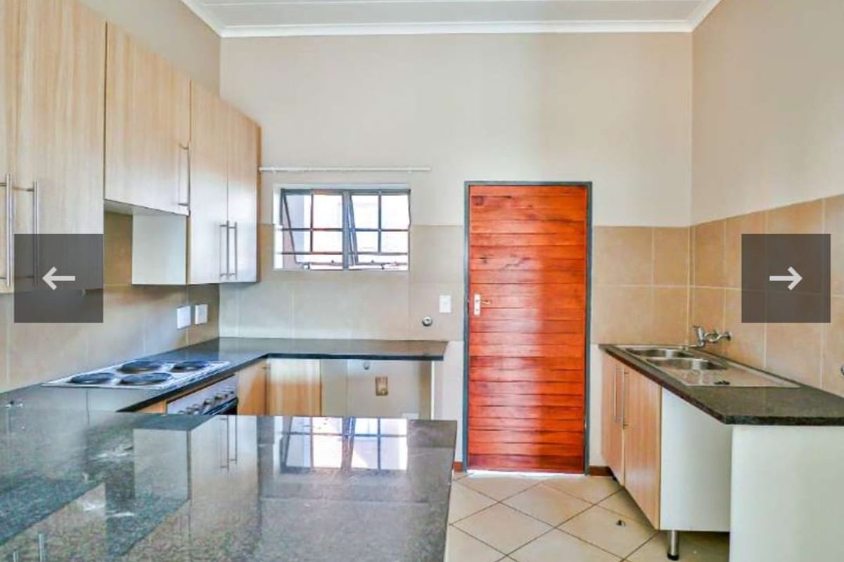 A functional kitchen featuring light wood cabinetry, granite countertops, an electric hob, and a double basin sink with tiled splashbacks.