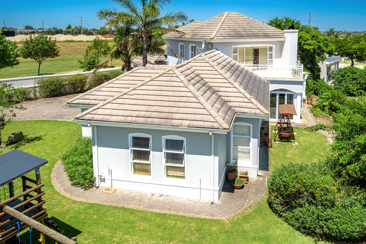 Aerial view of the property showing the tiled roof structure, rear garden, paved pathways, and upper-level balcony.