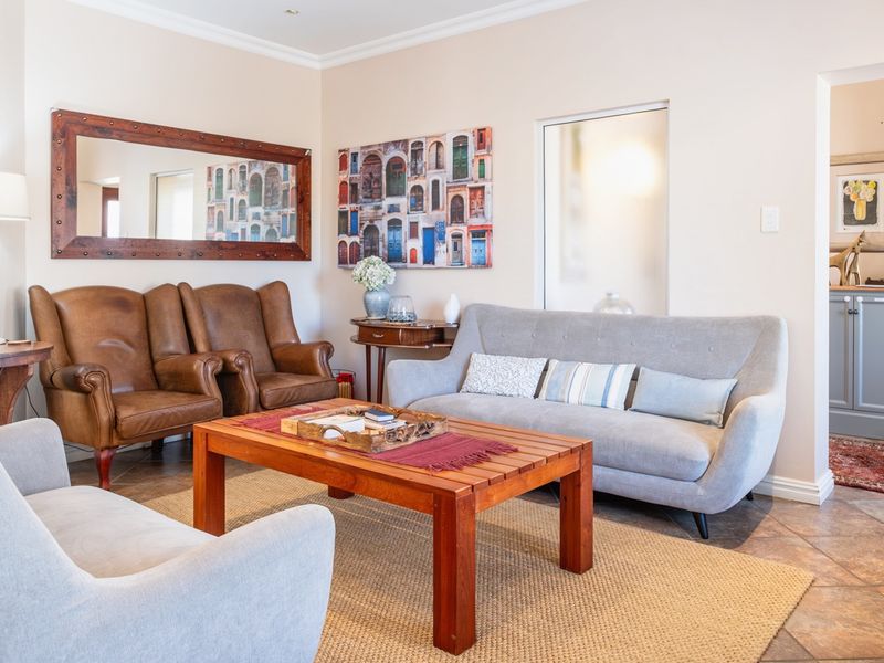 A well-maintained living room featuring tiled flooring, cove cornicing, and built-in cabinetry, offering a comfortable and inviting space.