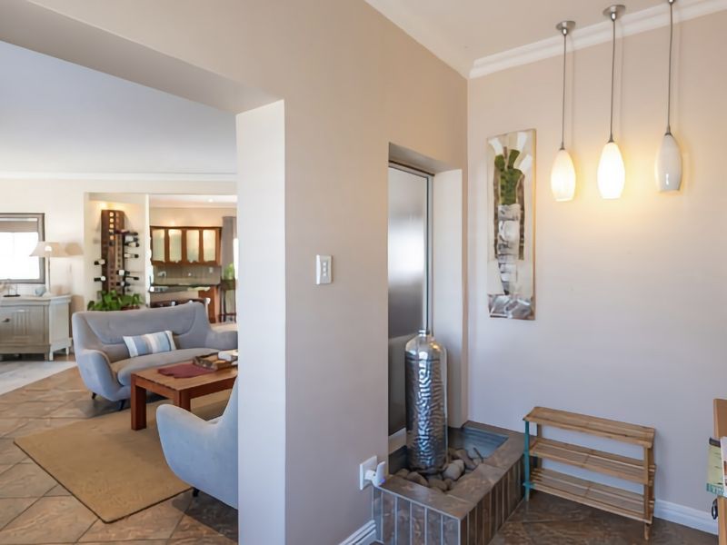 An open-plan living area featuring tiled flooring, a unique built-in indoor water feature, and modern pendant lighting, creating a connected and spacious atmosphere.