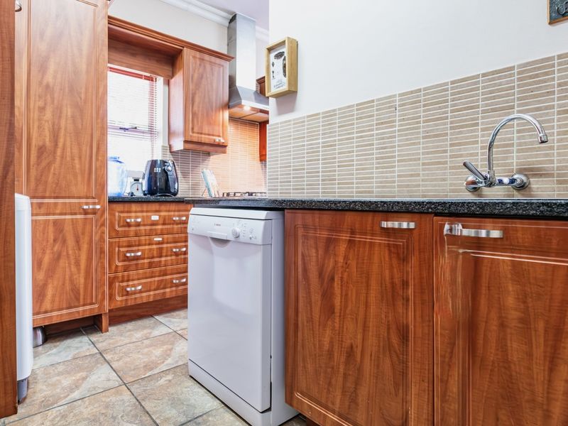 A functional kitchen featuring warm-toned wooden cabinetry, granite countertops, a tiled backsplash, and integrated stainless steel appliances.