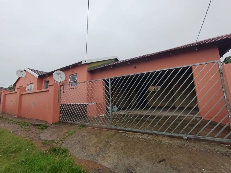Front exterior view of a single-story house featuring a metal sliding gate, perimeter wall, and tiled roof.