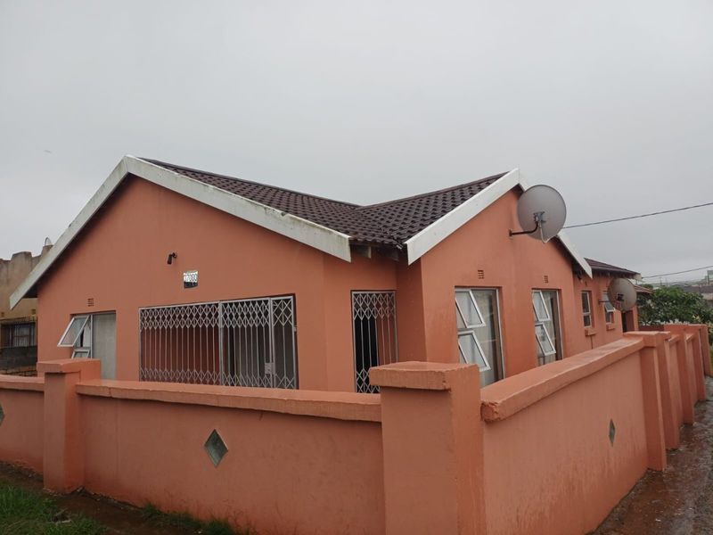 Exterior view of a single-story house featuring a tiled roof, security gates on windows, and a perimeter boundary wall.