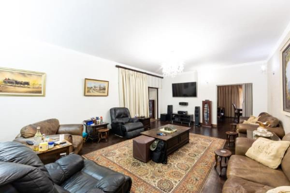 Spacious living room featuring dark hardwood flooring, neutral walls, and decorative crown molding, providing a comfortable and versatile area for relaxation.