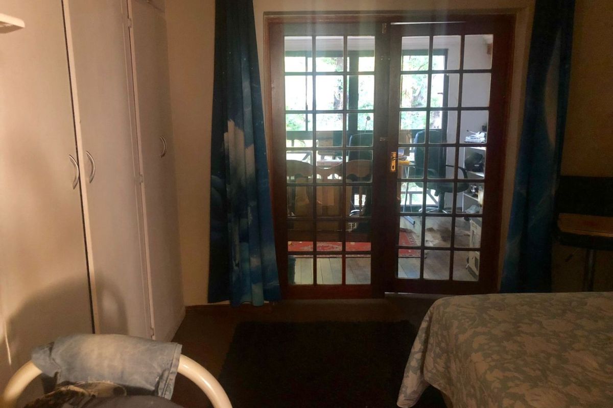 Bedroom featuring built-in cupboards and wooden-framed french doors providing access to an outdoor area.
