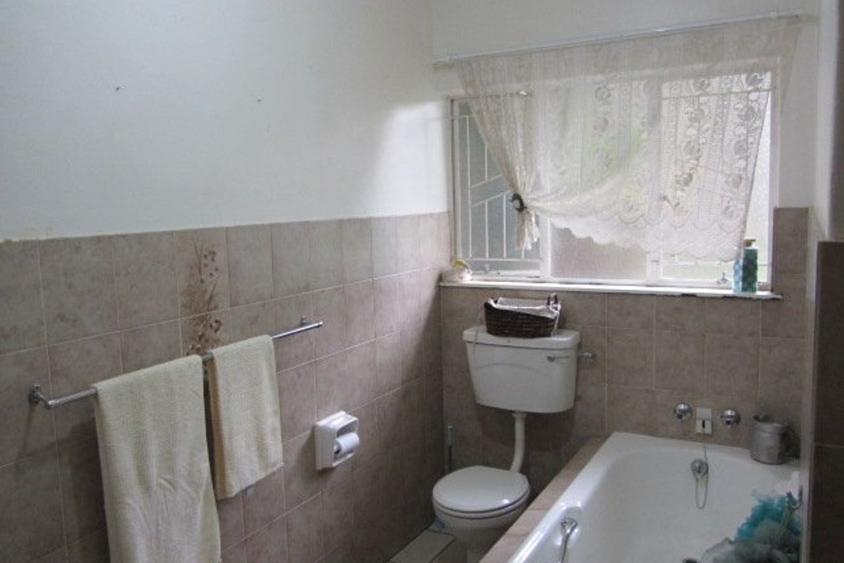 A dated bathroom featuring a standard bathtub, toilet, and neutral wall tiling. The space would benefit from modern fixtures and updated finishes.