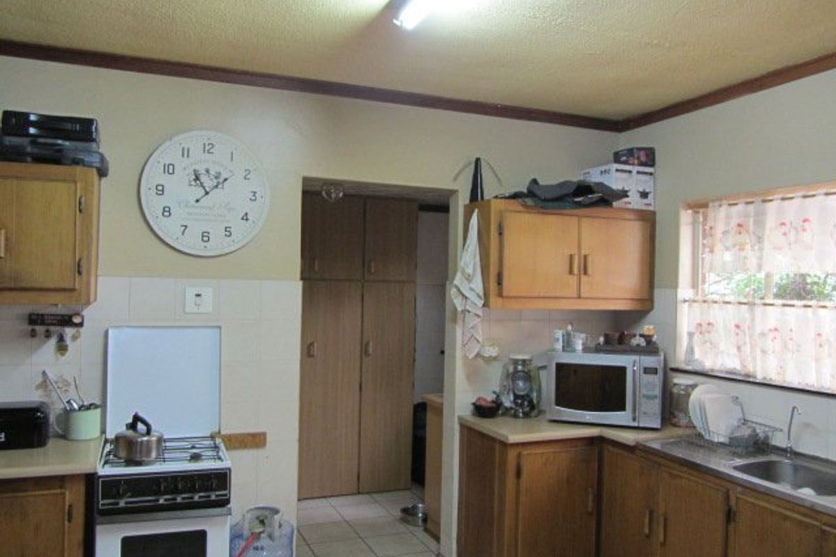 A functional kitchen featuring wooden cabinetry, tiled backsplash, a gas stove, and a separate pantry area with built-in storage cupboards.