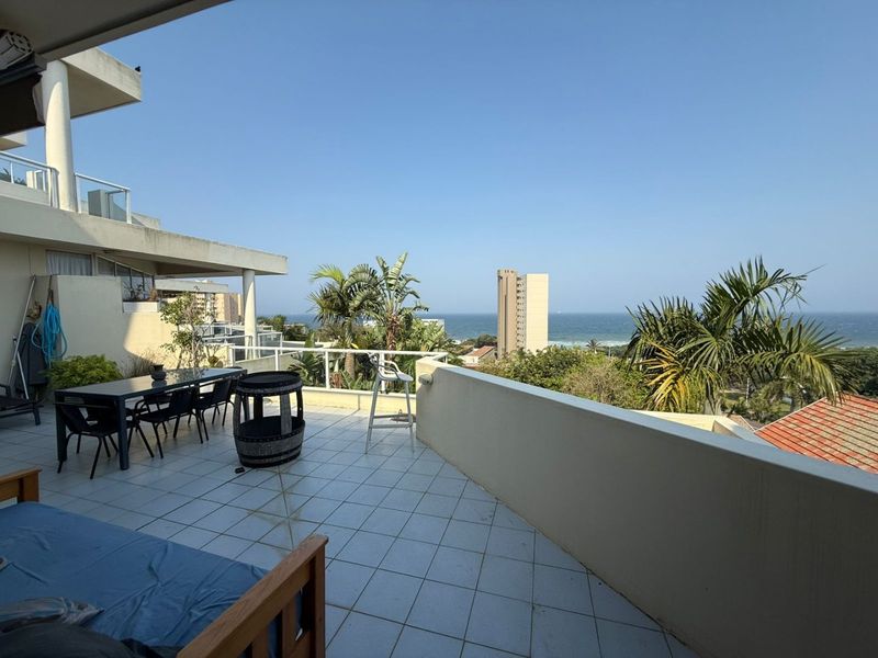Spacious balcony featuring tiled flooring, glass balustrades, and expansive ocean views, providing an ideal outdoor space for relaxation and entertainment.