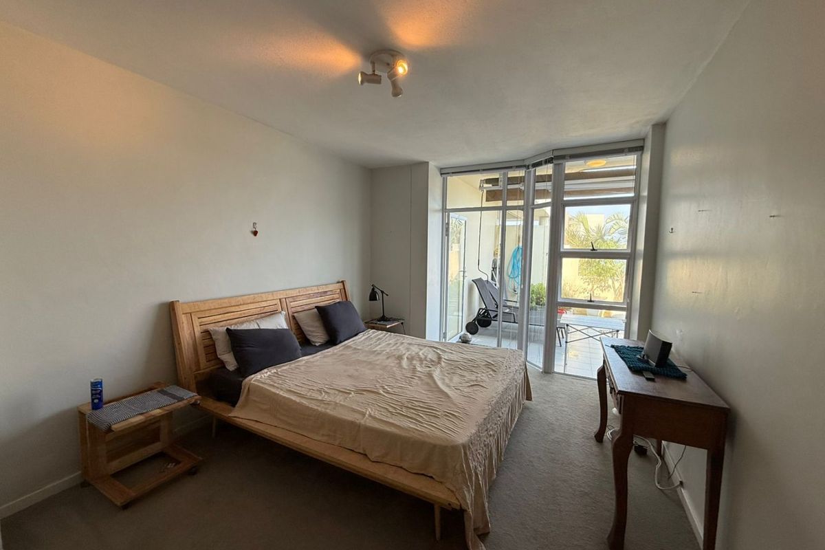 A bedroom featuring carpeted flooring, a ceiling spotlight, and a large sliding glass door providing access to an outdoor patio area.