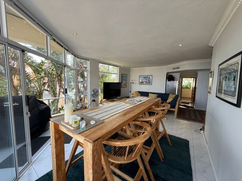 Spacious open-plan living and dining area featuring large sliding glass doors, tiled flooring, and recessed lighting, offering a bright and airy atmosphere.