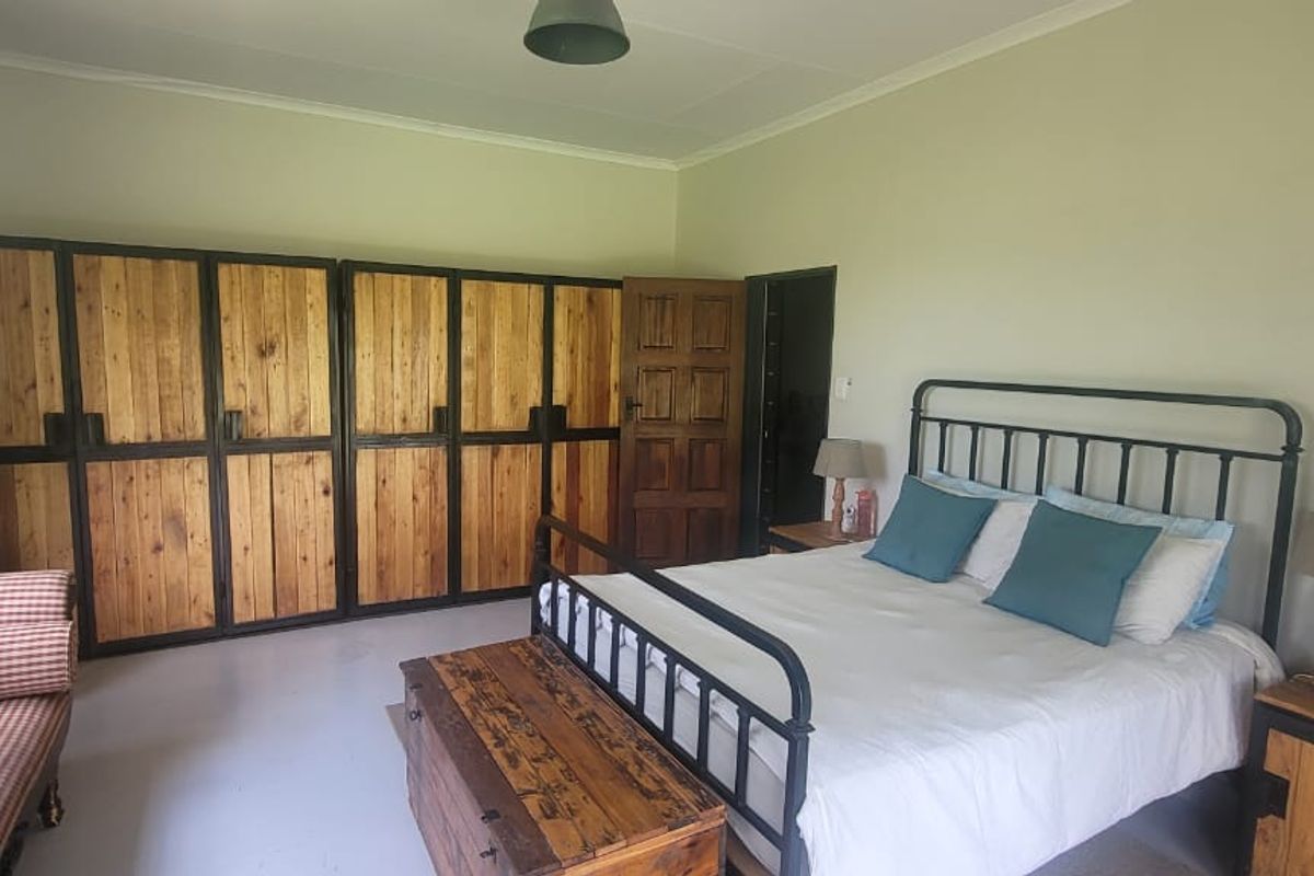 A spacious bedroom featuring large built-in wooden wardrobes, neutral wall finishes, and a classic wooden door, offering a functional and rustic living space.