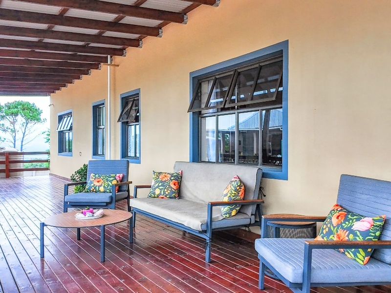 A spacious covered patio featuring timber decking and a timber-framed roof structure, offering a comfortable outdoor living space.