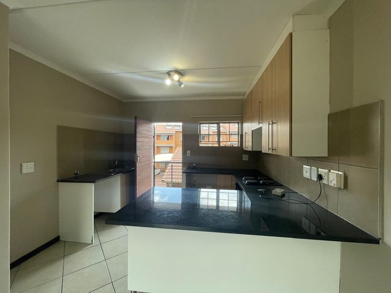 A functional kitchen featuring granite countertops, built-in cabinetry, a hob, and tiled flooring, offering a clean and practical workspace.