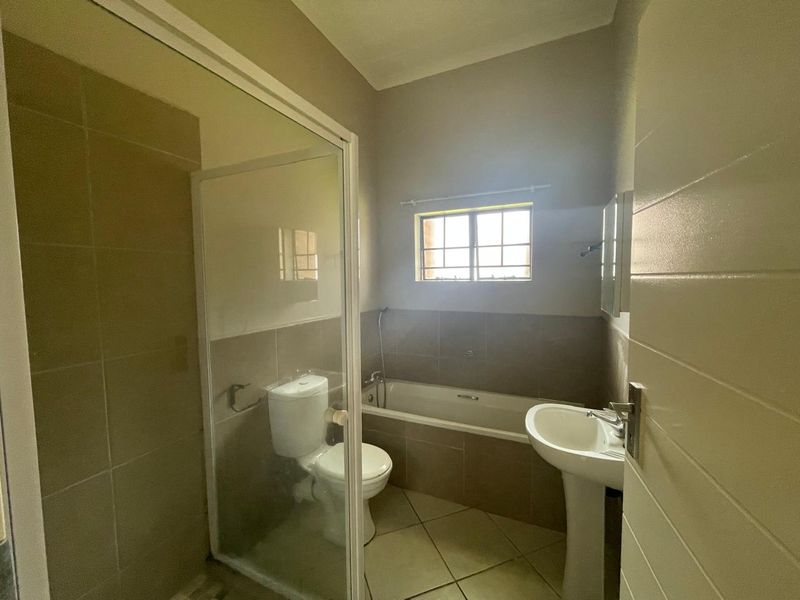 A functional bathroom featuring a pedestal basin, toilet, bathtub, and a separate shower enclosure with tiled finishes throughout.