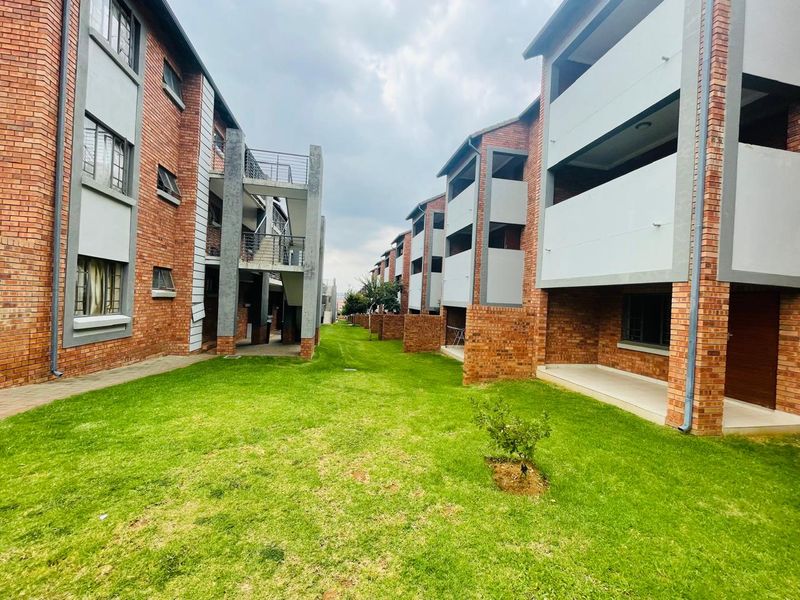 View of the apartment complex exterior featuring face brick facades, communal lawn areas, and private balconies.