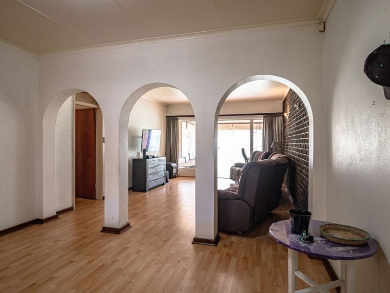 Spacious living area featuring distinctive arched doorways and an exposed brick feature wall, providing a unique architectural character to the home.