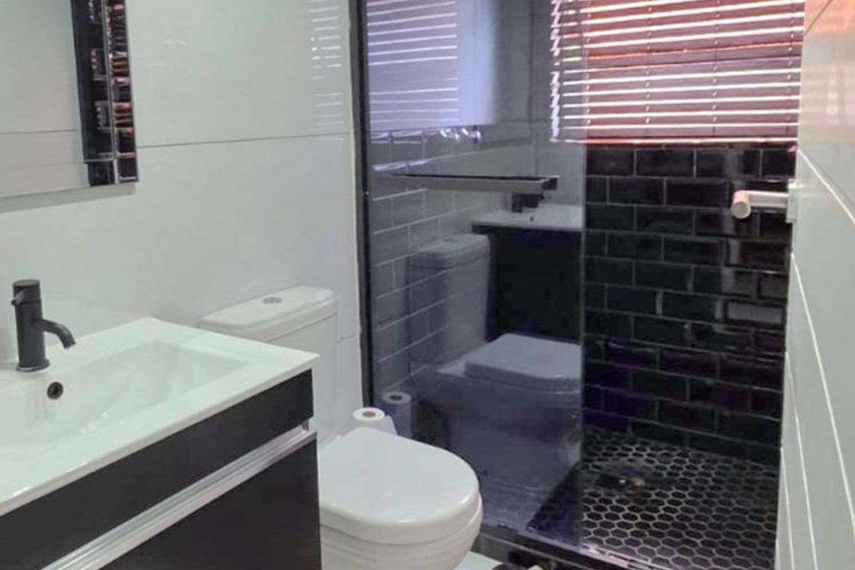 Modern bathroom featuring a floating vanity, glass-enclosed shower with black subway tiling, and contemporary fixtures.