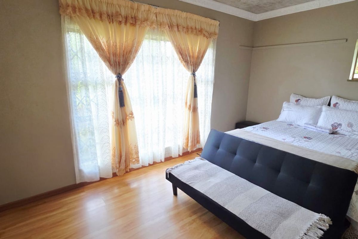 A bedroom featuring laminate flooring, built-in cupboards, and security bars on the windows, offering a functional and well-lit living space.