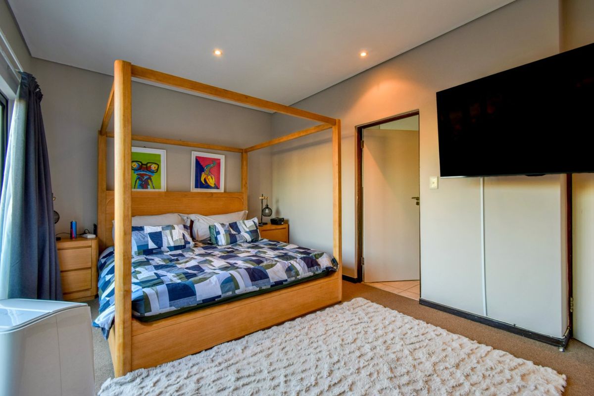 A well-maintained bedroom featuring neutral wall tones, recessed downlighting, and carpeted flooring, providing a comfortable and functional living space.