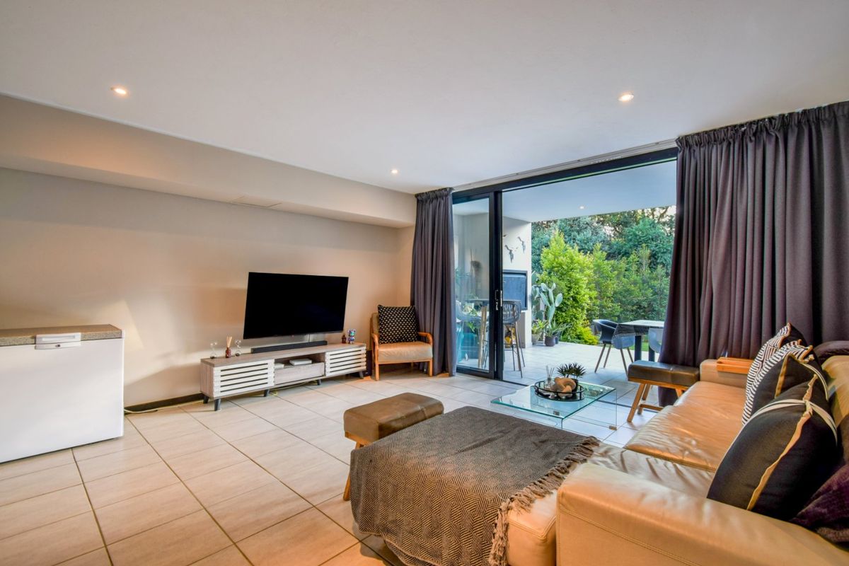 Spacious living room featuring tiled flooring, recessed lighting, and large sliding glass doors providing seamless access to the outdoor patio area.
