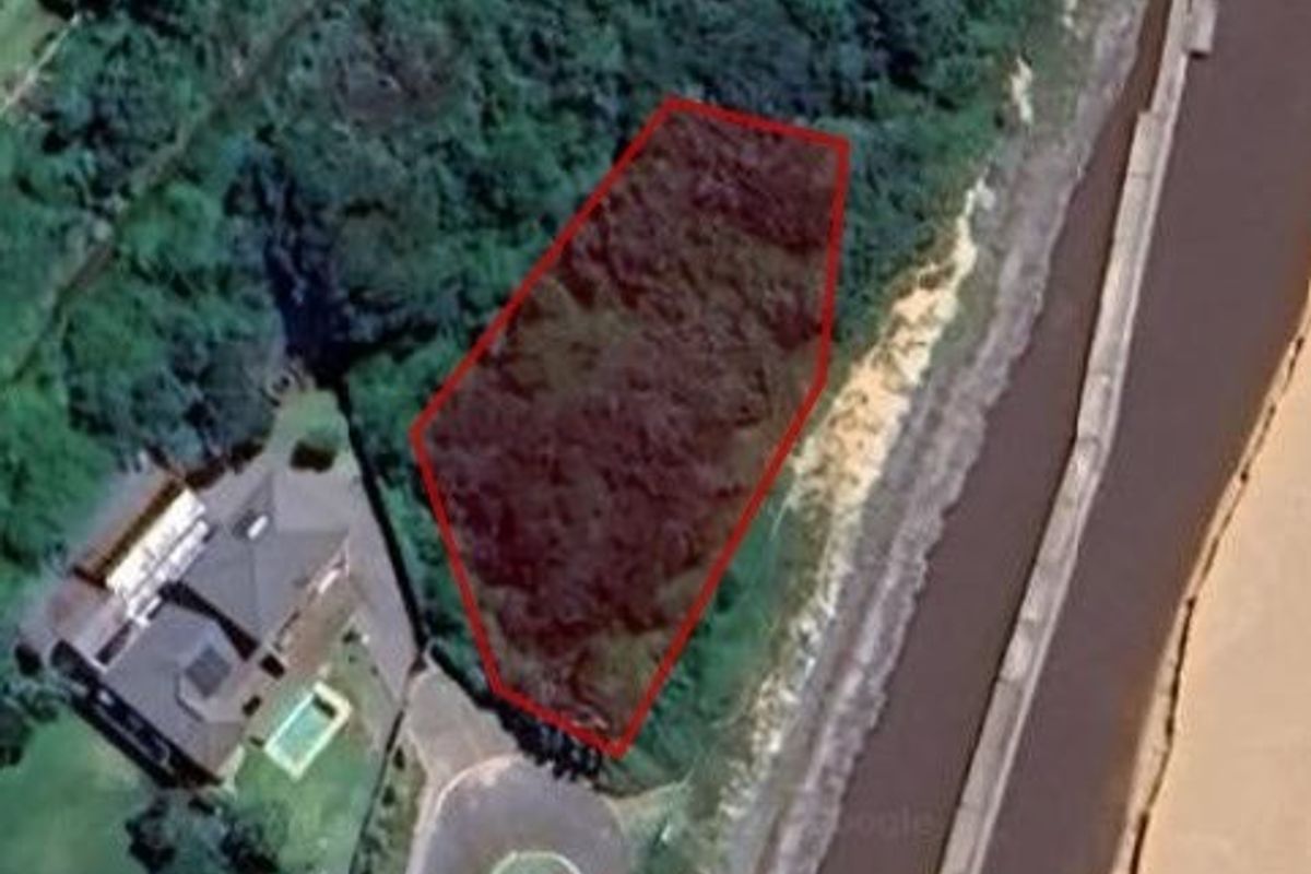Aerial view of a vacant residential plot outlined in red, situated in a coastal or riverfront neighborhood.