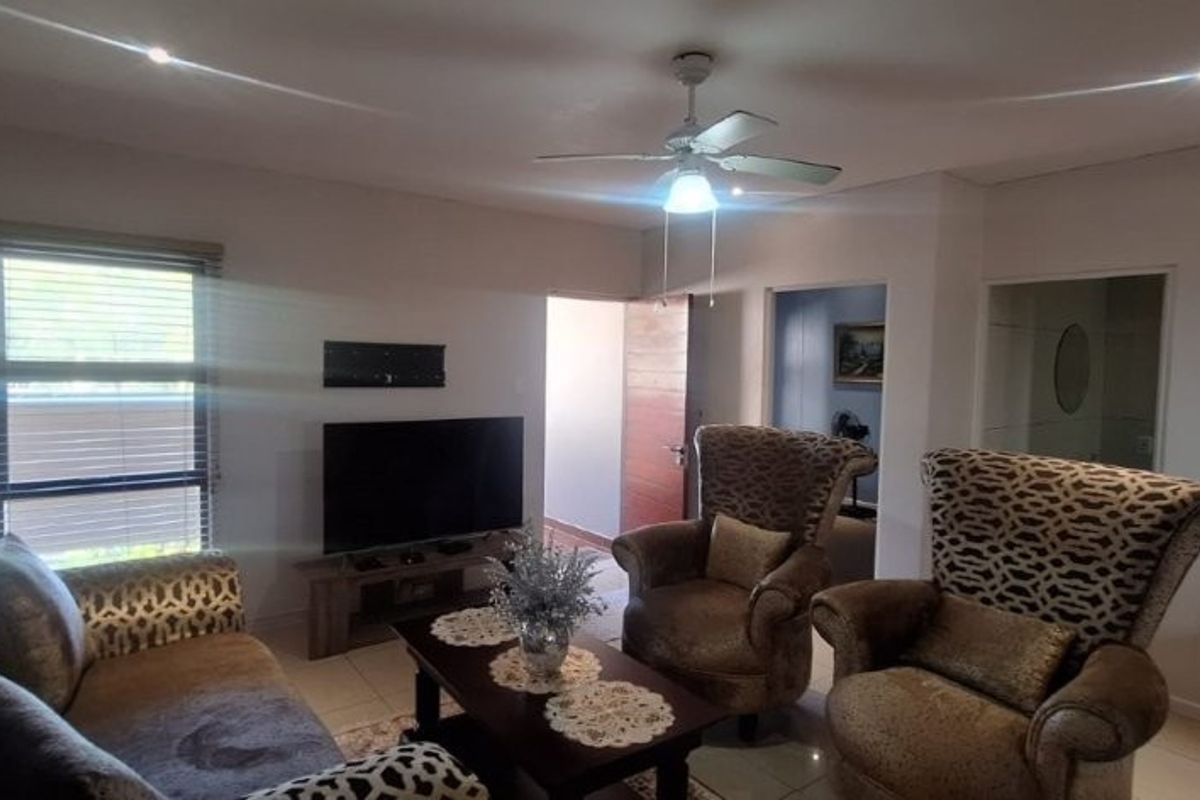 A comfortable living room featuring tiled flooring, a ceiling fan, and recessed lighting, providing a functional and well-lit space for relaxation.