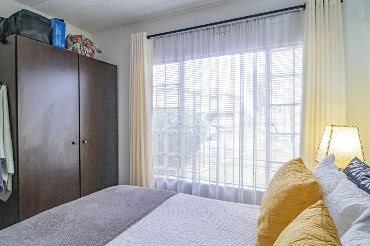 A functional bedroom featuring a built-in wardrobe and a large window that allows for natural light.