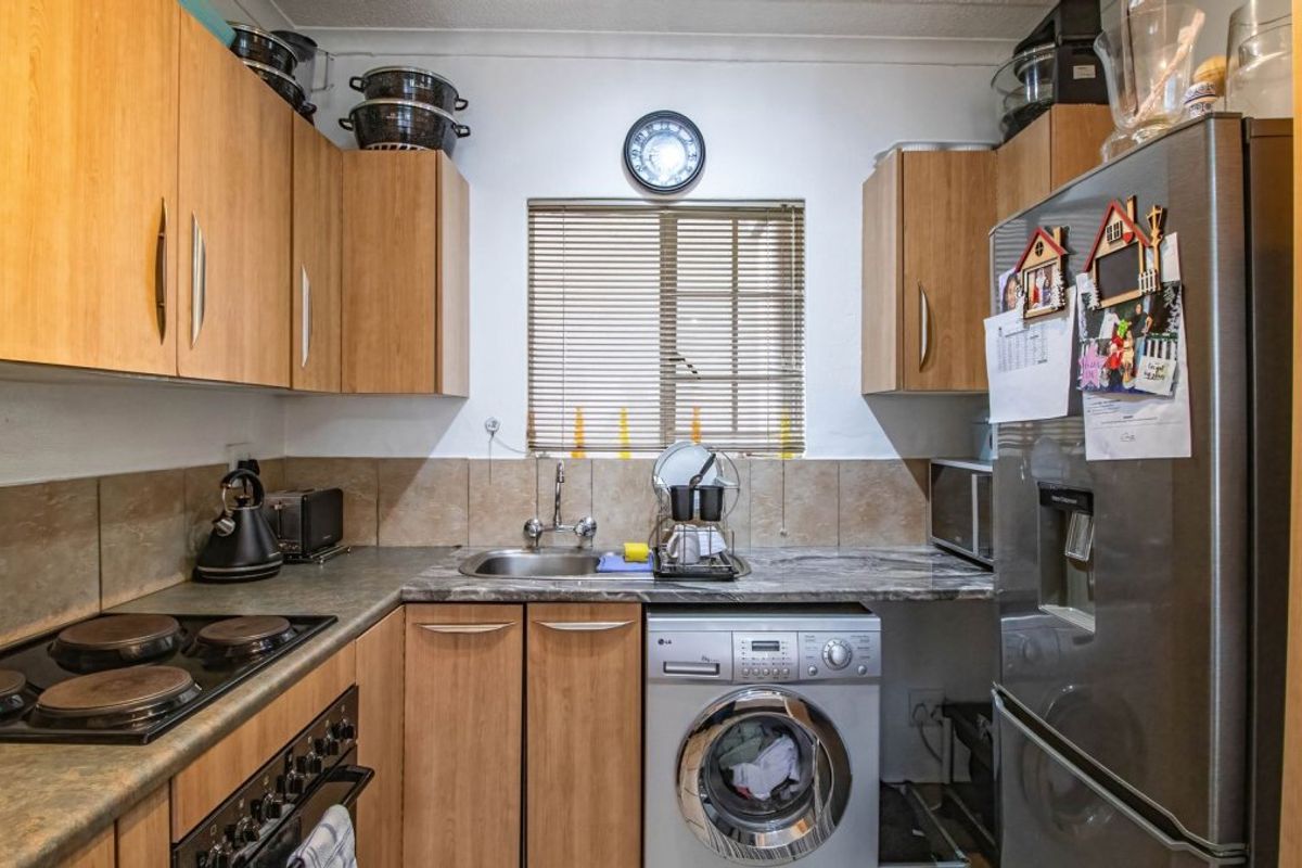 Compact kitchen featuring laminate cabinetry, stone-look countertops, built-in electric hob and oven, and integrated space for a washing machine.