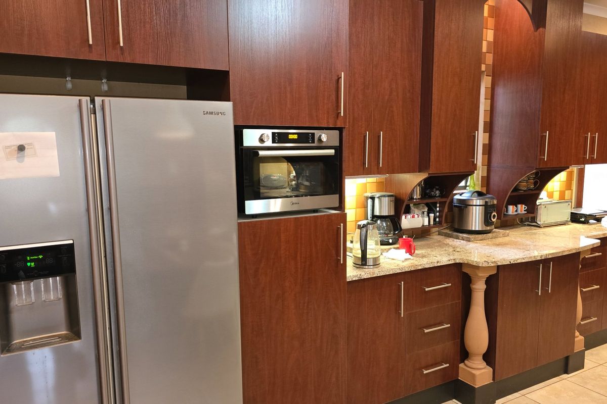 A functional kitchen featuring dark wood cabinetry, granite countertops, a built-in oven, and tiled flooring, offering ample storage and workspace.