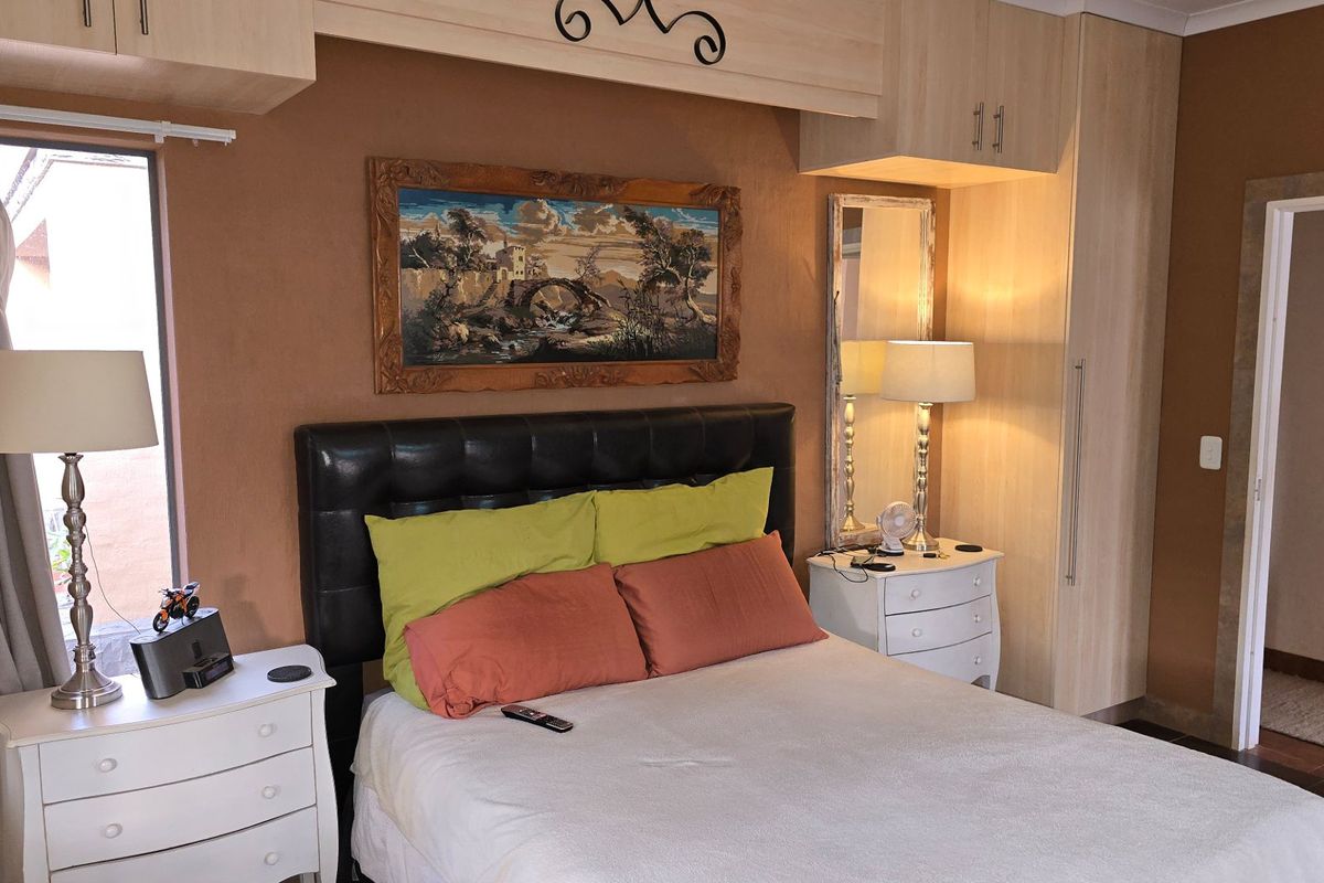 A bedroom featuring built-in cupboards and overhead storage cabinetry, providing functional storage space within the room.