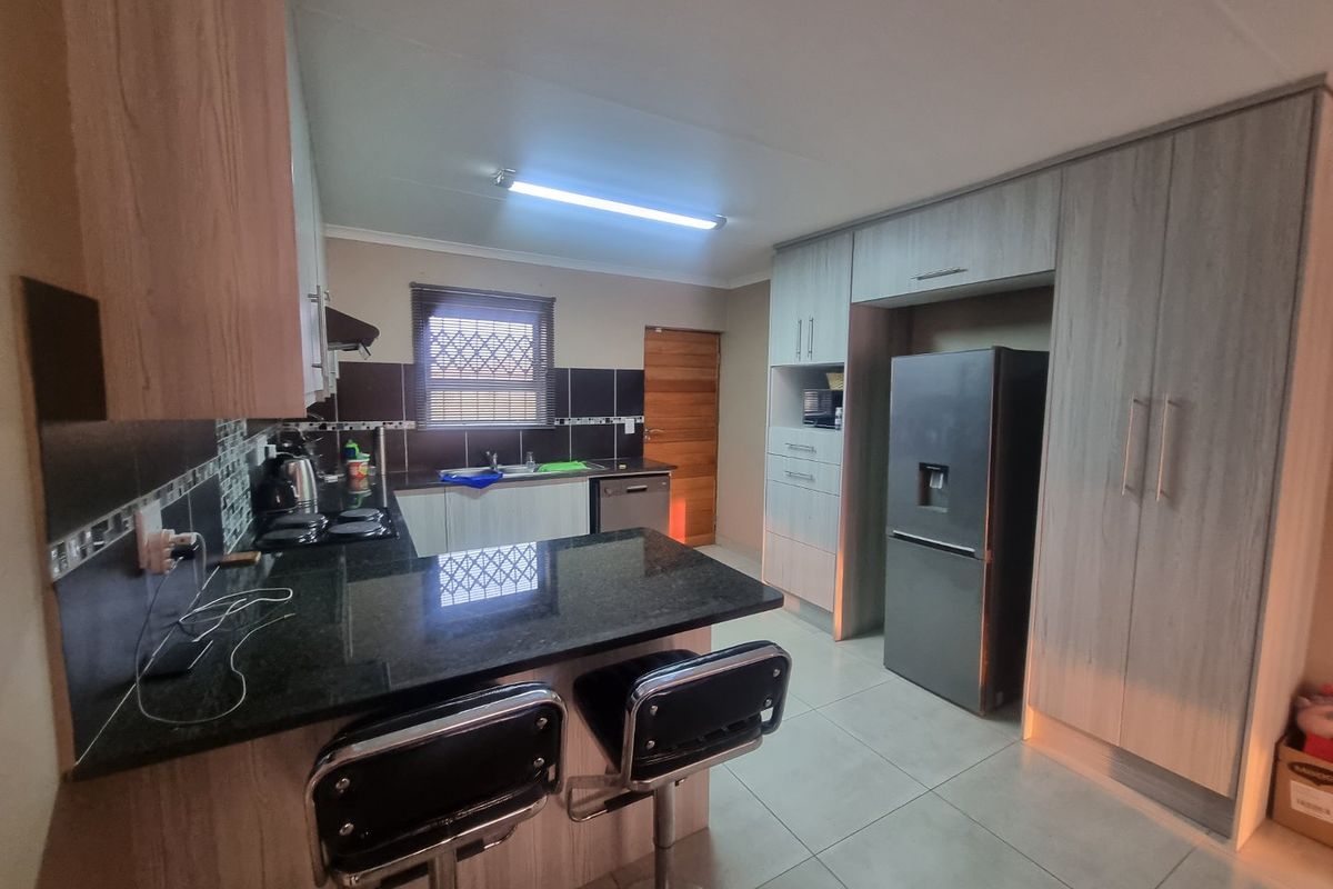 Modern kitchen featuring granite countertops, ample built-in cabinetry, tiled backsplash, and integrated appliances, offering a functional and well-maintained cooking space.