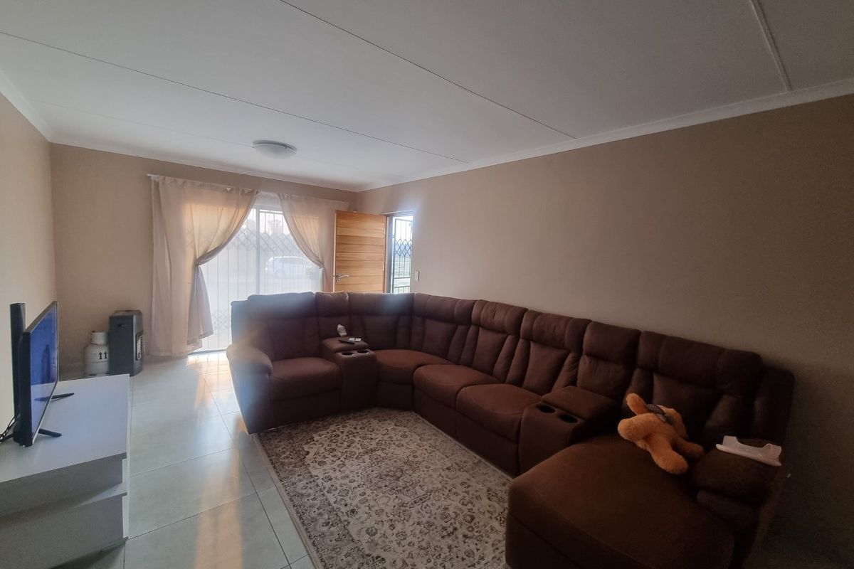 A spacious living room featuring neutral wall tones, tiled flooring, and a sliding glass door providing access to the exterior.