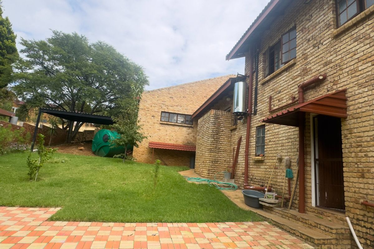 Rear view of the face brick house featuring a lawn, paved patio area, and solar water heating system.
