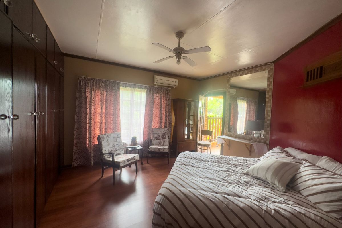 Spacious bedroom featuring built-in cupboards, laminate flooring, a ceiling fan, and a split-system air conditioner with direct access to an outdoor area.